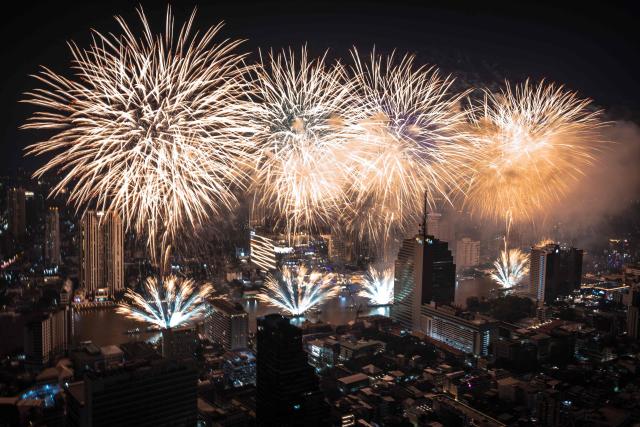 TOPSHOT - Fireworks light up the midnight sky over the Chao Phraya River during 2026 New Year's Day celebrations in Bangkok on January 1, 2026. (Photo by Chanakarn Laosarakham / AFP)