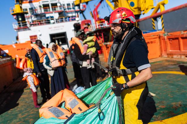 Search and Rescue (SAR) team's leader of the “Ocean Viking” rescue ship distributes life jackets as they prepare to evacuate migrants to RHIBs (Rigid inflatable boat) from the oil tanker the Maridive 703, in the search-and-rescue zone in international waters between Malta and Tunisia, on December 31, 2025. 33 migrants were rescued by crew members of the migrants rescue ship "Ocean Viking" operated by the French NGO SOS Mediterranee. They had been stranded on the oil tanker the 'Maridive 703' since their initial rescue 5 days ago in the joint search zone between Malta and Tunisia in international Mediterranean waters. (Photo by Sameer Al-DOUMY / AFP)