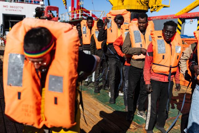 A crew member of the “Ocean Viking” rescue ship demonstrates how to wear a life jacket to migrants as they prepare to evacuate migrants from the oil tanker the 'Maridive 703' to RHIBs (Rigid inflatable boats) in the search-and-rescue zone of the international waters between Malta and Tunisia, on December 31, 2025. 33 migrants were rescued by crew members of the migrants rescue ship "Ocean Viking" operated by the French NGO SOS Mediterranee. They had been stranded on the oil tanker the 'Maridive 703' since their initial rescue 5 days ago in the joint search zone between Malta and Tunisia in international Mediterranean waters. (Photo by Sameer Al-DOUMY / AFP)
