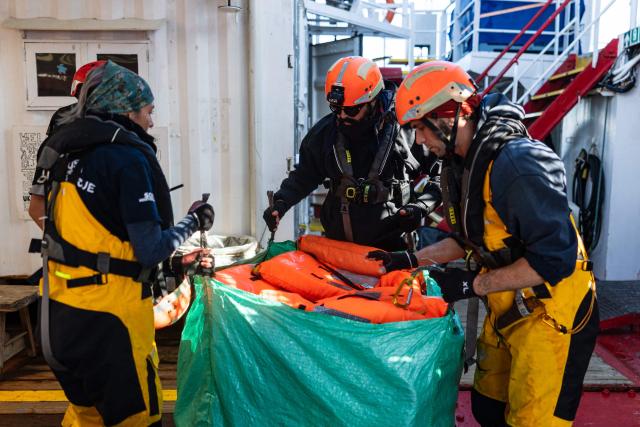Crew members of the “Ocean Viking” rescue ship collect life jackets after evacuating migrants from the oil tanker the 'Maridive 703' in the search-and-rescue zone of the international waters between Malta and Tunisia, on December 31, 2025. 33 migrants were rescued by crew members of the migrants rescue ship "Ocean Viking" operated by the French NGO SOS Mediterranee. They had been stranded on the oil tanker the 'Maridive 703' since their initial rescue 5 days ago in the joint search zone between Malta and Tunisia in international Mediterranean waters. (Photo by Sameer Al-DOUMY / AFP)