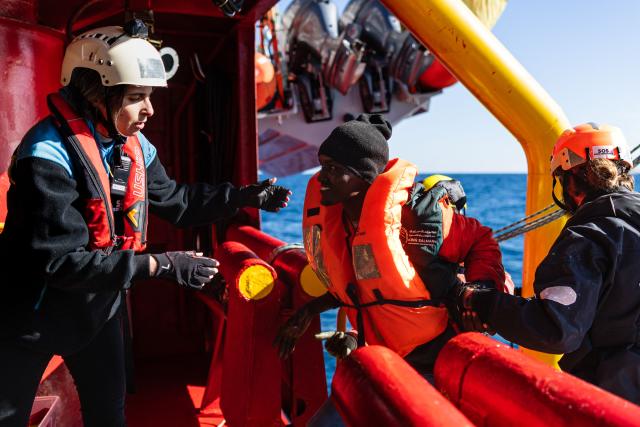 Crew members help a migrant board the “Ocean Viking” rescue ship after being evacuated by RHIB (Rigid inflatable boat) from the oil tanker the 'Maridive 703' in the search-and-rescue zone of the international waters between Malta and Tunisia, on December 31, 2025. 33 migrants were rescued by crew members of the migrants rescue ship "Ocean Viking" operated by the French NGO SOS Mediterranee. They had been stranded on the oil tanker the 'Maridive 703' since their initial rescue 5 days ago in the joint search zone between Malta and Tunisia in international Mediterranean waters. (Photo by Sameer Al-DOUMY / AFP)