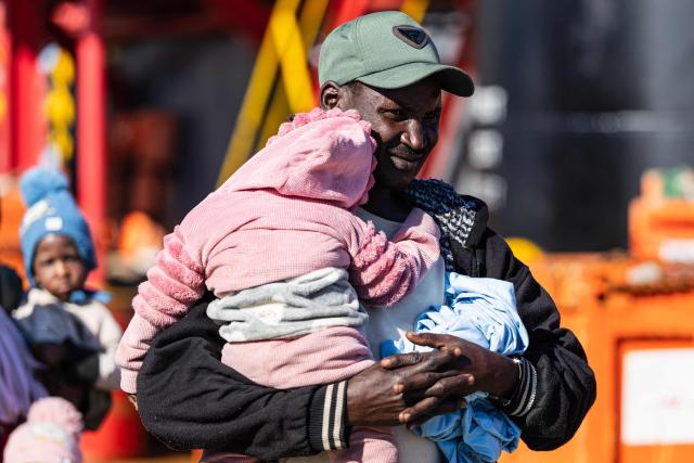 A migrant holds a child as they prepare to board a RHIB (Rigid inflatable boat) as crew members of the “Ocean Viking” rescue ship evacuate them from the oil tanker the 'Maridive 703' in the search-and-rescue zone of the international waters between Malta and Tunisia, on December 31, 2025. 33 migrants were rescued by crew members of the migrants rescue ship "Ocean Viking" operated by the French NGO SOS Mediterranee. They had been stranded on the oil tanker the 'Maridive 703' since their initial rescue 5 days ago in the joint search zone between Malta and Tunisia in international Mediterranean waters. (Photo by Sameer Al-DOUMY / AFP)