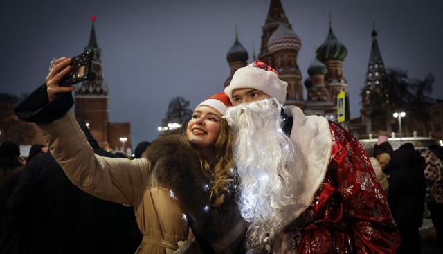 Revellers wearing Santa hats take a selfie during New Year's Eve celebrations on the edge of the closed Red Square in Moscow on December 31, 2025. (Photo by TATYANA MAKEYEVA / AFP)