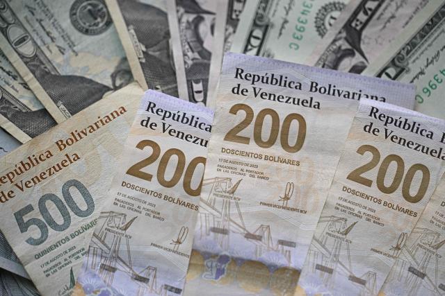 (FILES) Picture of Venezuelan bolivar and US dollar bills taken in Caracas on September 30, 2025. On December 31, 2025, the Central Bank of Venezuela (BCV) valued the dollar at 301.37 bolivars (Venezuelan currency), a price valid until January 2, representing an increase of 479.25% compared to the 52.02 bolivars set by the issuing entity at the beginning of 2025. (Photo by Federico PARRA / AFP)