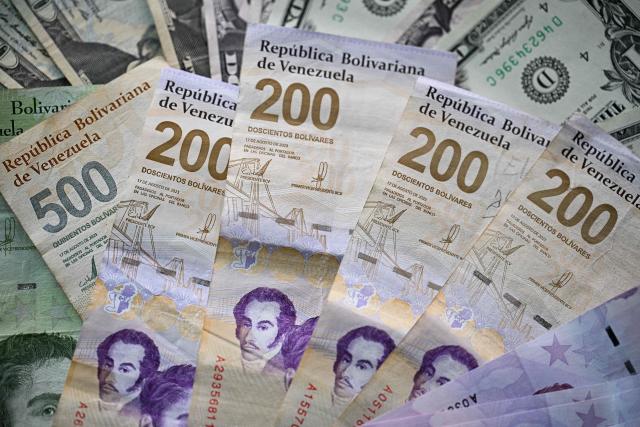 (FILES) Picture of Venezuelan bolivar and US dollar bills taken in Caracas on September 30, 2025. On December 31, 2025, the Central Bank of Venezuela (BCV) valued the dollar at 301.37 bolivars (Venezuelan currency), a price valid until January 2, representing an increase of 479.25% compared to the 52.02 bolivars set by the issuing entity at the beginning of 2025. (Photo by Federico PARRA / AFP)