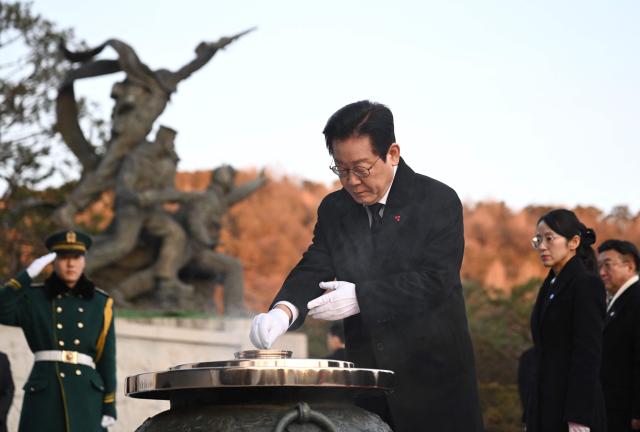 South Korean President Lee Jae Myung burns incense as he visits the National Cemetery with his cabinet members in Seoul at the beginning of the new year on January 1, 2026. (Photo by Jung Yeon-je / AFP)