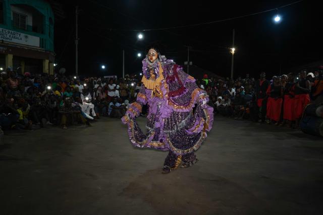 A member of the Freetown dance troop dressed in a masquerade costume dances in front of a crowd during the Sierra Leone New Year's Cultural Festival in Kabala on January 1, 2026. (Photo by Gemma Bonfiglioli / AFP)