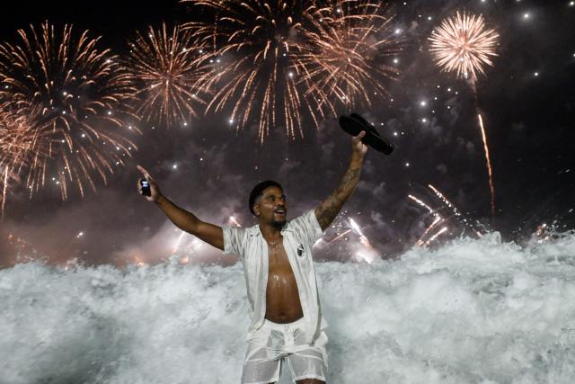 TOPSHOT - A man celebrates during the traditional New Year's fireworks at Copacabana Beach in Rio de Janeiro, Brazil, on January 1, 2026. Rio de Janeiro received, on December 30, 2025, the title of the world’s largest New Year’s Eve celebration from the Guinness World Records, a recognition of its famous massive festivity with live music shows by the sea. (Photo by TERCIO TEIXEIRA / AFP)