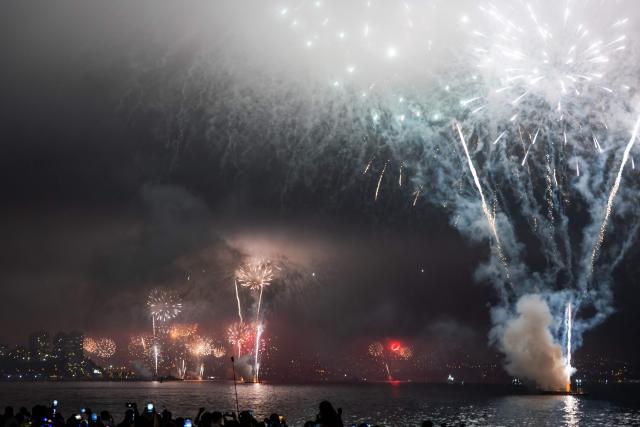 People watch the fireworks explode in the port of Valparaiso on the coast of Chile during New Year celebrations on January 1, 2026. (Photo by Javier TORRES / AFP)