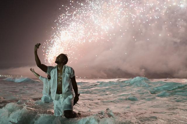 A man celebrates during the traditional New Year's fireworks at Copacabana Beach in Rio de Janeiro, Brazil, on January 1, 2026. Rio de Janeiro received, on December 30, 2025, the title of the world’s largest New Year’s Eve celebration from the Guinness World Records, a recognition of its famous massive festivity with live music shows by the sea. (Photo by TERCIO TEIXEIRA / AFP)