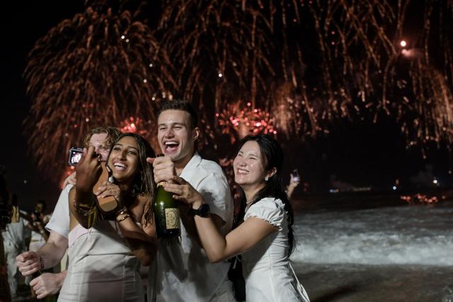 TOPSHOT - People pose for a selfie as they celebrate during the traditional New Year's fireworks at Copacabana Beach in Rio de Janeiro, Brazil, on January 1, 2026. Rio de Janeiro received, on December 30, 2025, the title of the world’s largest New Year’s Eve celebration from the Guinness World Records, a recognition of its famous massive festivity with live music shows by the sea. (Photo by TERCIO TEIXEIRA / AFP)