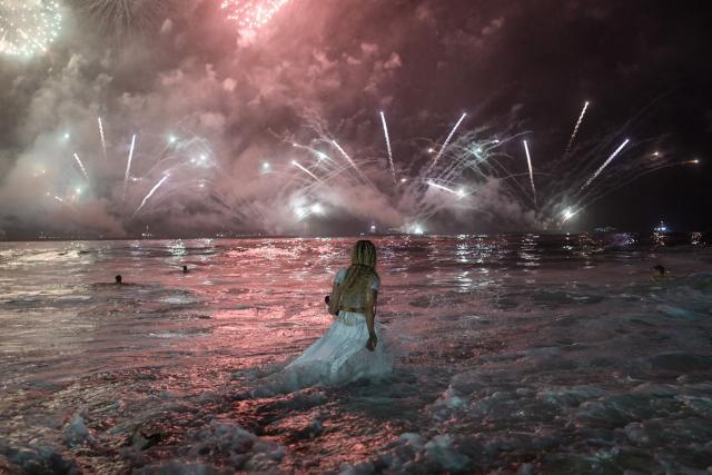 A woman watches the traditional New Year's fireworks from the water at Copacabana Beach in Rio de Janeiro, Brazil, on January 1, 2026. Rio de Janeiro received, on December 30, 2025, the title of the world’s largest New Year’s Eve celebration from the Guinness World Records, a recognition of its famous massive festivity with live music shows by the sea. (Photo by TERCIO TEIXEIRA / AFP)