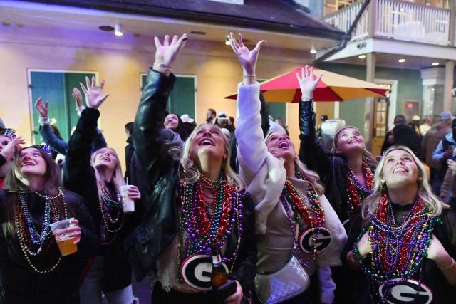 Fans of the Georgia Bulldogs football team reach for beads while celebrating the New Year at the French Quarter in New Orleans, Louisiana, on January 1, 2026. (Photo by Octavio JONES / AFP)