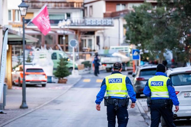 Police officers walk at the site of an explosion that ripped through a bar in Crans-Montana on January 1, 2026. Several people were killed and others injured when an explosion ripped through a bar in the luxury Alpine ski resort town of Crans Montana, Swiss police said early on January 1. (Photo by MAXIME SCHMID / AFP)