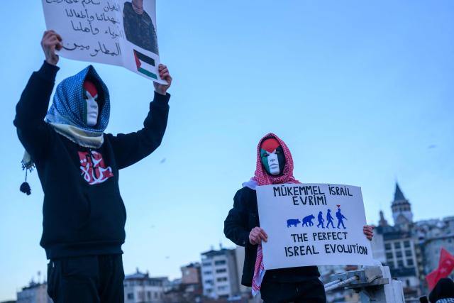 Demonstrators hold placards as they demonstrate in solidarity with the Palestinian people amid the ongoing war between Israel and the Palestinian Hamas group in the Gaza enclave, at the Galata Bridge in Istanbul on January 1, 2026. (Photo by Yasin AKGUL / AFP)
