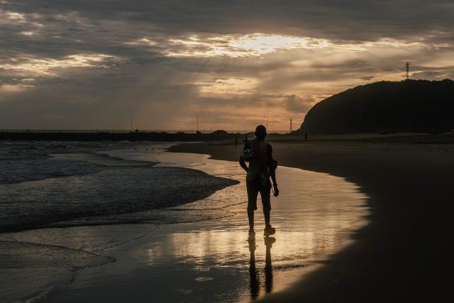 A holidaymaker walks as the sun rises on the South beach on New Year's day in Durban on January 1, 2026. (Photo by RAJESH JANTILAL / AFP)