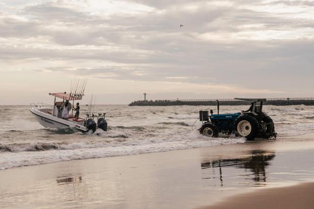 A tractor pushes a small boat of fishermen and women into the Indian ocean on New Year's day on the South beach of Durban on January 1, 2026. (Photo by RAJESH JANTILAL / AFP)