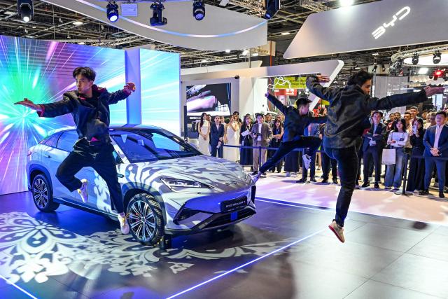 (FILES) Practitioners perform martial art next to a BYD Sealion 7 electric vehicle (EV) by Chinese car manufacturer BYD on display at Singapore Motorshow in Singapore on January 9, 2025. Chinese auto giant BYD sold 2.26 million electric vehicles last year, a company statement at the Hong Kong Stock Exchange showed on January 1, 2026, setting a new record for any firm globally. (Photo by Roslan RAHMAN / AFP)