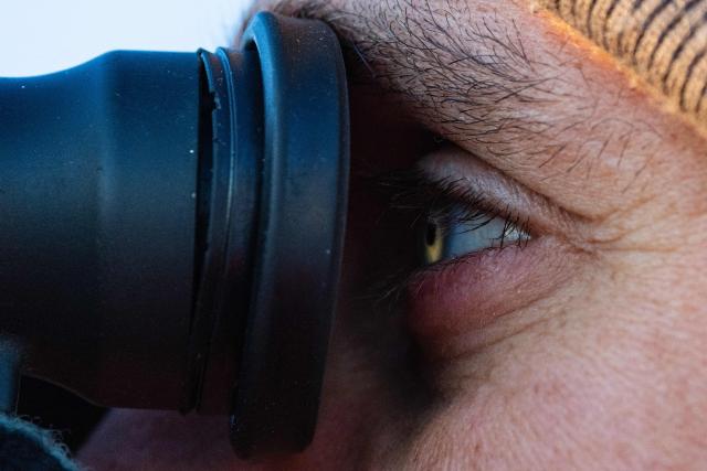 A crew member of the migrants rescue ship "Ocean Viking" operated by the NGO SOS Mediterranee, uses binoculars as they patrol at the search-and-rescue zone of the international waters between Malta and Tunisia, on December 31, 2025. (Photo by Sameer Al-DOUMY / AFP)