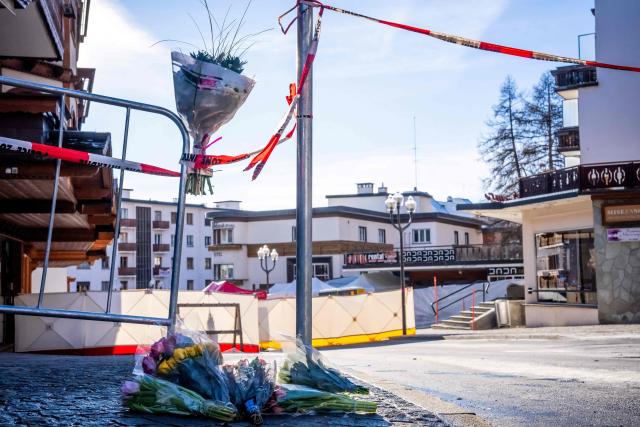 A photograph taken on January 1, 2026 shows flowers and candles laid on the ground near the bar Le Constellation following a fire that ripped through the venue in Crans-Montana, during New Year's Eve celebrations. Several dozen people are presumed dead and around 100 injured after a fire ripped through a crowded bar in the luxury Swiss ski resort town of Crans-Montana, police said early January 1, 2026. (Photo by MAXIME SCHMID / AFP)