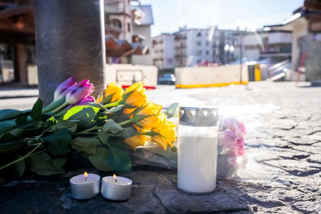 A photograph taken on January 1, 2026 shows flowers and candles laid on the ground near the bar Le Constellation following a fire that ripped through the venue in Crans-Montana, during New Year's Eve celebrations. Several dozen people are presumed dead and around 100 injured after a fire ripped through a crowded bar in the luxury Swiss ski resort town of Crans-Montana, police said early January 1, 2026. (Photo by MAXIME SCHMID / AFP)