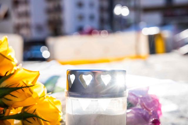 A photograph taken on January 1, 2026 shows flowers and candles laid on the ground near the bar Le Constellation following a fire that ripped through the venue in Crans-Montana, during New Year's Eve celebrations. Several dozen people are presumed dead and around 100 injured after a fire ripped through a crowded bar in the luxury Swiss ski resort town of Crans-Montana, police said early January 1, 2026. (Photo by MAXIME SCHMID / AFP)