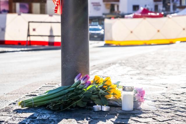 A photograph taken on January 1, 2026 shows flowers and candles laid on the ground near the bar Le Constellation following a fire that ripped through the venue in Crans-Montana, during New Year's Eve celebrations. Several dozen people are presumed dead and around 100 injured after a fire ripped through a crowded bar in the luxury Swiss ski resort town of Crans-Montana, police said early January 1, 2026. (Photo by MAXIME SCHMID / AFP)