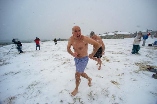 Revelers run into the ocean during a snow storm on New Year’s day on January 1, 2026 in Boston, Massachusetts. The polar plunge on New Year's day dates back over 100 years in Boston, but many people, mainly members of the L-Street Brownies, take daily swims 365 days a year into the ocean. (Photo by Joseph Prezioso / AFP)