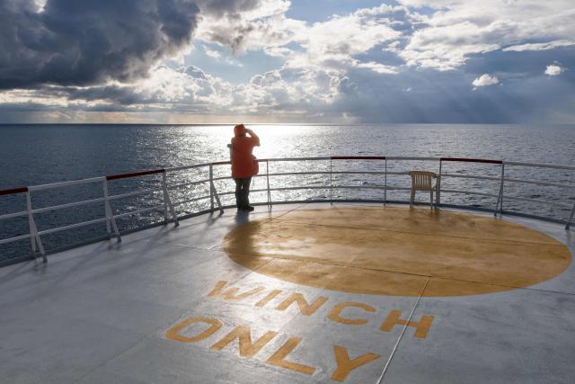 A crew member of the rescue ship "Ocean Viking" operated by the NGO SOS Mediterranee, uses binoculars as the ship patrols the search-and-rescue zone of the international waters near Malta, on January 1, 2026. (Photo by Sameer Al-DOUMY / AFP)
