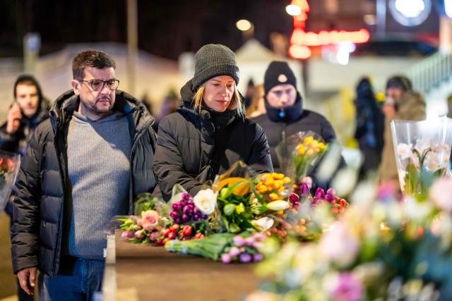 Mourners gather in front of flowers and candles laid near the site where a fire ripped through a crowded bar during New Year's Eve celebrations in the Alpine ski resort town of Crans-Montana on January 1, 2026. Around 40 people were killed and over 100 injured when a fire ripped through a crowded bar in the luxury Swiss ski resort town of Crans-Montana as young revellers rang in the new year, police said. Police, firefighters and rescuers rushed to the popular resort, which is set to host the Ski World Cup from January 30, after the fire broke out in the early hours of New Year's Day. (Photo by MAXIME SCHMID / AFP)