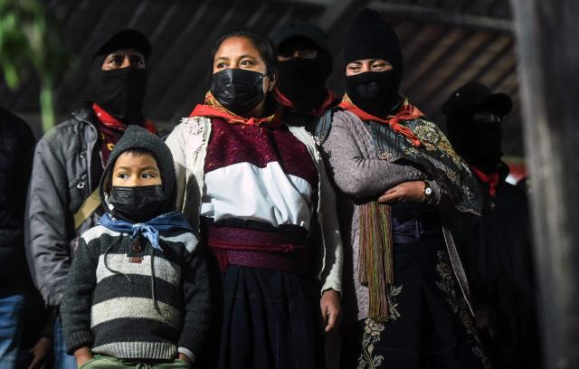A family of members of the now demobilized Zapatista Army of National Liberation (EZLN) guerrilla group, led by insurgent Subcommander Moises (out of frame), takes part in the celebration of the 32th anniversary of their first armed uprising - on January 1, 1994 - against the Mexican government, at the autonomous community of Caracol number 3 in Oventic, Chiapas State, Mexico on December 31, 2025. (Photo by Alejandro MELENDEZ / AFP)