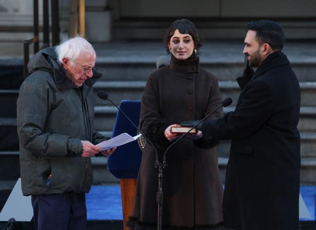 US Senator Bernie Sanders swears in New York mayor Zohran Mamdani as his wife Rama Duwaji holds the Koran during his public inauguration ceremony followed by a block party at City Hall in New York on January 1, 2026. Mamdani, the young upstart of the US left, was sworn in Thursday to take over as New York mayor for a term sure to see him cross swords with President Donald Trump. After the clocks struck midnight, bringing in 2026, Mamdani took his oath of office at an abandoned subway stop to begin managing the United States' largest city. He is New York's first Muslim mayor. (Photo by ANGELA WEISS / AFP)