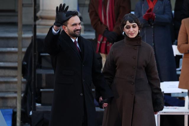 New York mayor Zohran Mamdani waves next to his wife Rama Duwaji during his public inauguration ceremony followed by a block party at City Hall in New York on January 1, 2026. Mamdani, the young upstart of the US left, was sworn in Thursday to take over as New York mayor for a term sure to see him cross swords with President Donald Trump. After the clocks struck midnight, bringing in 2026, Mamdani took his oath of office at an abandoned subway stop to begin managing the United States' largest city. He is New York's first Muslim mayor. (Photo by ANGELA WEISS / AFP)