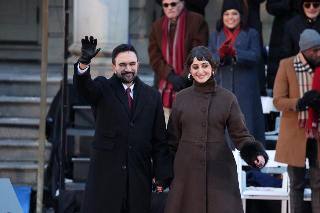 New York mayor Zohran Mamdani waves next to his wife Rama Duwaji during his public inauguration ceremony followed by a block party at City Hall in New York on January 1, 2026. Mamdani, the young upstart of the US left, was sworn in Thursday to take over as New York mayor for a term sure to see him cross swords with President Donald Trump. After the clocks struck midnight, bringing in 2026, Mamdani took his oath of office at an abandoned subway stop to begin managing the United States' largest city. He is New York's first Muslim mayor. (Photo by ANGELA WEISS / AFP)
