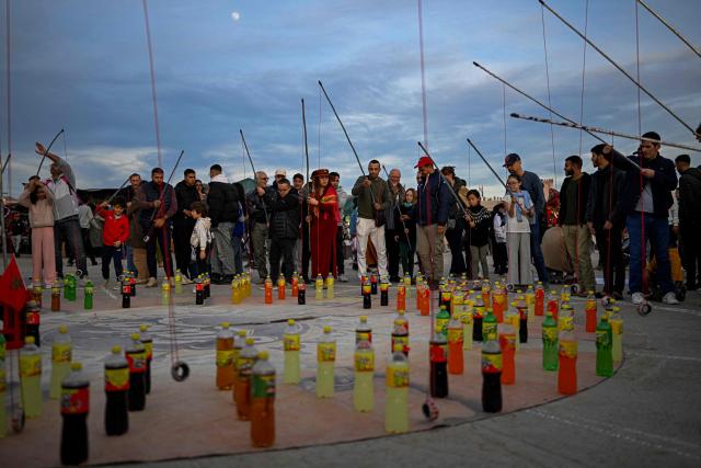 Visitors try to land a ring around the necks of soft drink bottles to catch one during a street vendor’s performance in Marrakesh's Jemaa el-Fna Square on January 1, 2026, during the Africa Cup of Nations (CAN) football tournament. (Photo by Khaled DESOUKI / AFP)