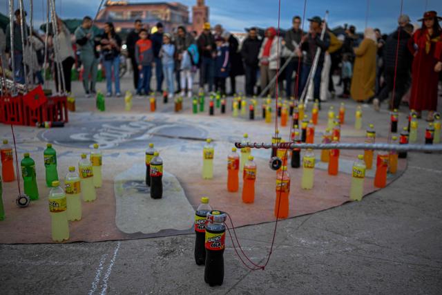 Visitors try to land a ring around the necks of soft drink bottles to catch one during a street vendor’s performance in Marrakesh's Jemaa el-Fna Square on January 1, 2026, during the Africa Cup of Nations (CAN) football tournament. (Photo by Khaled DESOUKI / AFP)