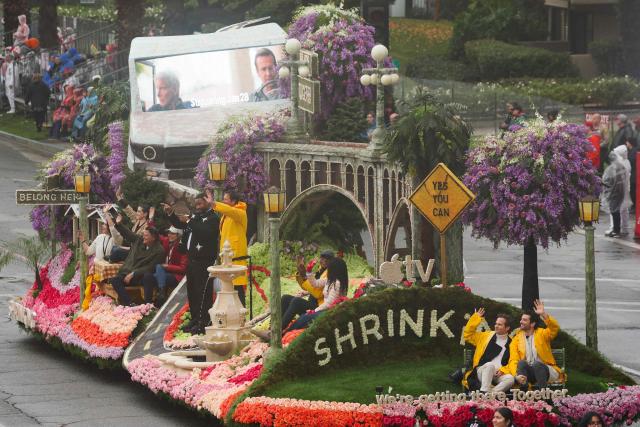 Actors Ted McGinley and Luke Tennie TKTK ride on the Apple TV and Warner Bros. Television Shrinking show float “We’re Getting There. Together.” in the rain during the 137th Rose Parade on New Years Day in Pasadena, California, on January 1, 2026. The parade features floral floats, marching bands and equestrian units to ring in the New Year along the 5.5 mile (8.8 km) route along Colorado Blvd in Pasadena. (Photo by Patrick T. Fallon / AFP)