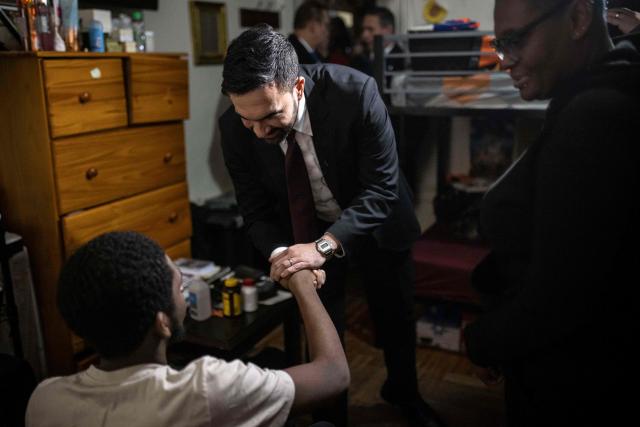 New York Mayor Zohran Mamdani shakes hands with a man as he visits the apartment of Nadege Romulus (R) in the Prospect Lefferts Gardens neighborhood of Brooklyn, New York, January 1, 2026, on his first day in office. Mamdani, the young upstart of the US left, was sworn in January 1 to take over as New York mayor for a term sure to see him cross swords with President Donald Trump. After the clocks struck midnight, bringing in 2026, Mamdani took his oath of office at an abandoned subway stop to begin managing the United States' largest city. He is New York's first Muslim mayor. (Photo by Dave Sanders / POOL / AFP)