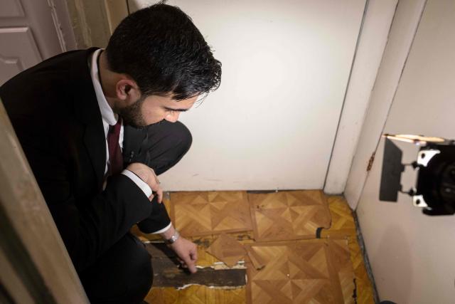 New York Mayor Zohran Mamdani checks the flooring as he visits the apartment of Nadege Romulus in the Prospect Lefferts Gardens neighborhood of Brooklyn, New York, January 1, 2026, on his first day in office. Mamdani, the young upstart of the US left, was sworn in January 1 to take over as New York mayor for a term sure to see him cross swords with President Donald Trump. After the clocks struck midnight, bringing in 2026, Mamdani took his oath of office at an abandoned subway stop to begin managing the United States' largest city. He is New York's first Muslim mayor. (Photo by Dave Sanders / POOL / AFP)