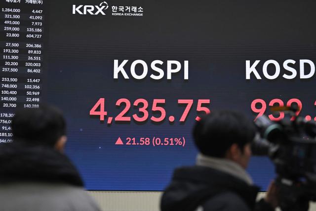 A cameraman films a stock index board showing South Korea's benchmark stock index after a ceremony celebrating the New Year's opening of the South Korea stock market at the Korea Exchange in Seoul on January 2, 2026. (Photo by Jung Yeon-je / AFP)