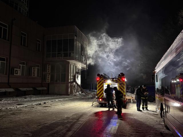 Firefighters stand near a damaged residential building following a Russian drone strike in Zaporizhzhia on January 2, 2026, amid the Russian invasion of Ukraine. (Photo by Darya NAZAROVA / AFP)