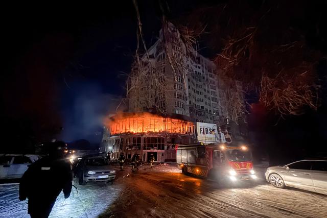 TOPSHOT - Firefighters stand near a residential building on fire following a Russian drone strike in Zaporizhzhia on January 2, 2026, amid the Russian invasion of Ukraine. (Photo by Darya NAZAROVA / AFP)