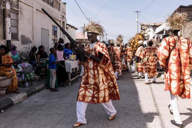 A member of the Ebileh hunting society carries a rifle in the streets ahead of the annual New Years Hunting Festival in Banjul on January 1, 2026. Deeply rooted in tradition, the festival has become a cherished New Year celebration in The Gambia, marked by music, dancing, and vibrant masquerades. Held in the capital city, Banjul, the event features a friendly yet fierce competition among hunting societies Ekun Baba, Odilleh, and the recently joined Gun Shot Hunting Society as they showcase striking animal head displays, masks, and elaborate costumes. (Photo by Muhamadou BITTAYE / AFP)