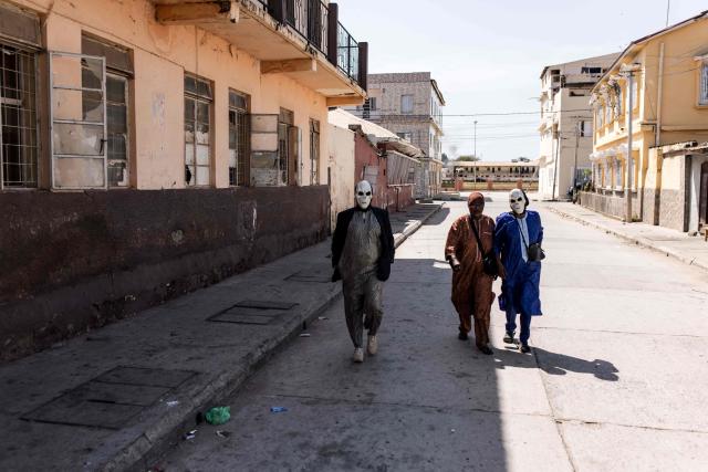 Two masked performers walk through the streets ahead of the annual New Years Hunting Festival in Banjul on January 1, 2026. Deeply rooted in tradition, the festival has become a cherished New Year celebration in The Gambia, marked by music, dancing, and vibrant masquerades. Held in the capital city, Banjul, the event features a friendly yet fierce competition among hunting societies Ekun Baba, Odilleh, and the recently joined Gun Shot Hunting Society as they showcase striking animal head displays, masks, and elaborate costumes. (Photo by Muhamadou BITTAYE / AFP)