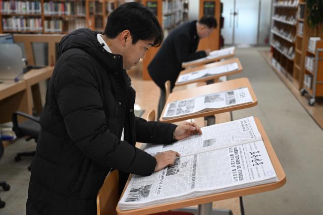 A visitor reads Rodong Sinmun (front), North Korea's top newspaper, at the National Library of Korea in Seoul on January 2, 2026. Packed with missile tests, thunderous tirades against the United States and tributes to the glories of the great leaders -- for decades, Seoul considered North Korea's top newspaper so dangerous its citizens were banned from reading it. But dovish President Lee Jae Myung is now seeking to ease tensions with Pyongyang and has joked that he doesn't believe the public will "become commies" just from reading it. That means from this week South Koreans can access the Rodong Sinmun -- meaning "Workers newspaper" -- at select locations without state approval. (Photo by Jung Yeon-je / AFP)