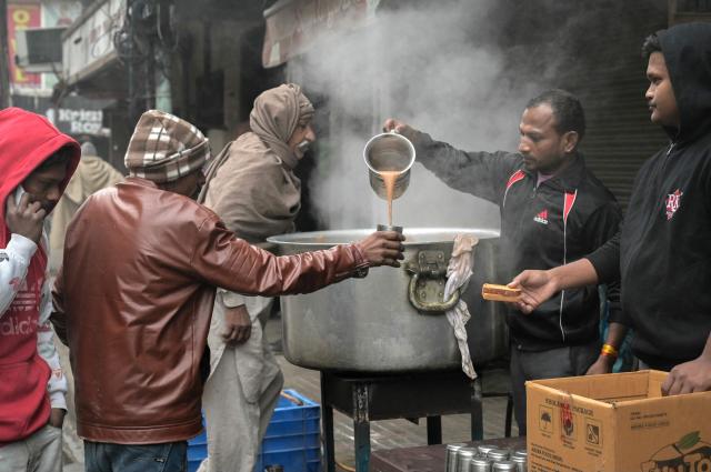 Volunteers distribute tea and biscuits along a street on a cold winter's day in Amritsar on January 2, 2026. (Photo by Narinder NANU / AFP)