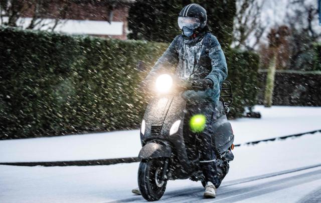 A driver rides a scooter on a snow-covered street, as a code yellow weather alert has been given for all of The Netherlands due to snow and icy roads, in Maasdam, on January 2, 2026. (Photo by Jeffrey Groeneweg / ANP / AFP) / Netherlands OUT