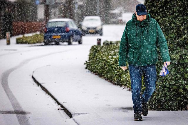 A pedestrian walks on a snow-covered street, as a code yellow weather alert has been given for all of The Netherlands due to snow and icy roads, in Maasdam, on January 2, 2026. (Photo by Jeffrey Groeneweg / ANP / AFP) / Netherlands OUT