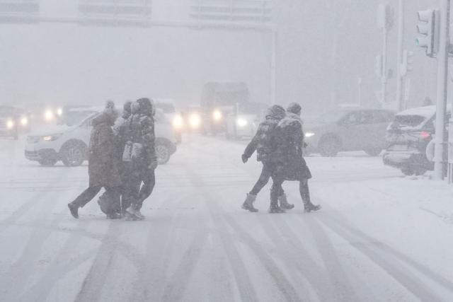 Pedestrians cross a snow-covered street in Aalborg, Denmark, as the country experiences a weather change due to a large low-pressure system. (Photo by Henning Bagger / Ritzau Scanpix / AFP) / Denmark OUT