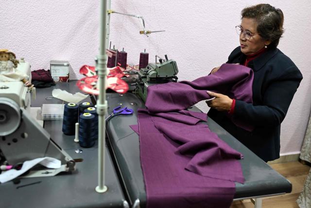Mexican seamstress and designer Olivia Trujillo Cortes, 63, works on a sewing machine on a garment for Mexico's President Claudia Sheinbaum in her workshop in San Pedro Martir, on the outskirts of Mexico City, on December 23, 2025. Mexican President Claudia Sheinbaum wore a purple, indigenous-embroidered dress at her first meeting with Donald Trump during the 2026 World Cup draw, a choice seen as symbolizing women's power. That week, The New York Times named her among the world's most stylish figures, highlighting her strategy of blending indigenous craftsmanship with modern elegance to send a political message. (Photo by Yuri CORTEZ / AFP)